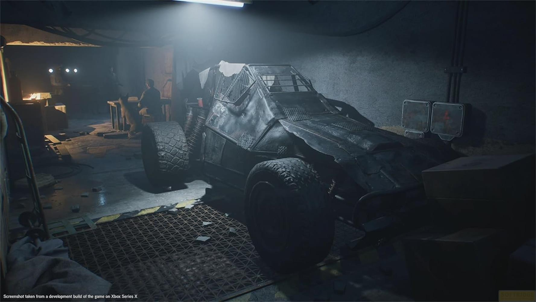 Ein gepanzertes Fahrzeug steht in einer dunklen Werkstatt mit einem Mann im Hintergrund.