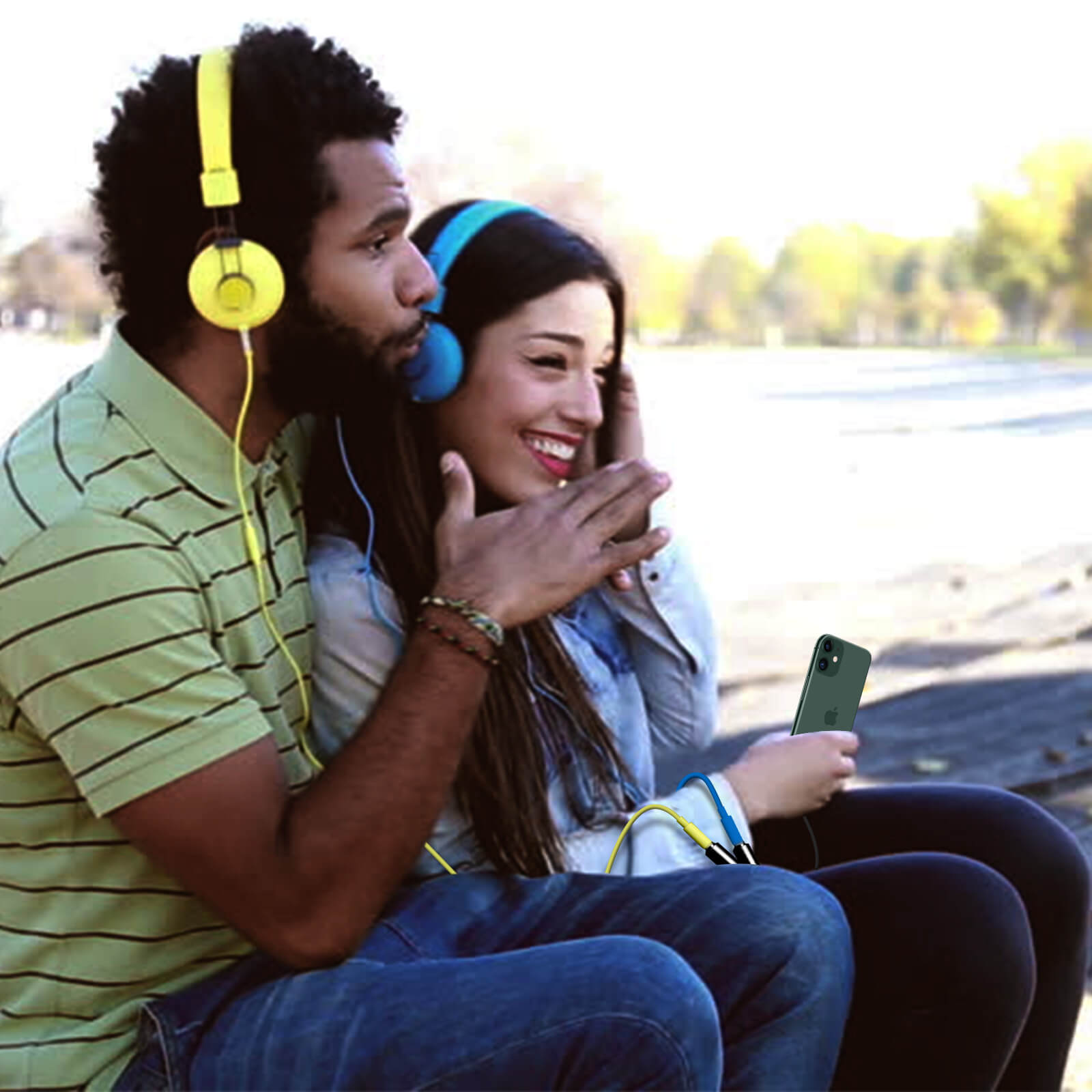 Un homme et une femme portant des écouteurs écoutent de la musique d'un téléphone à l'extérieur.