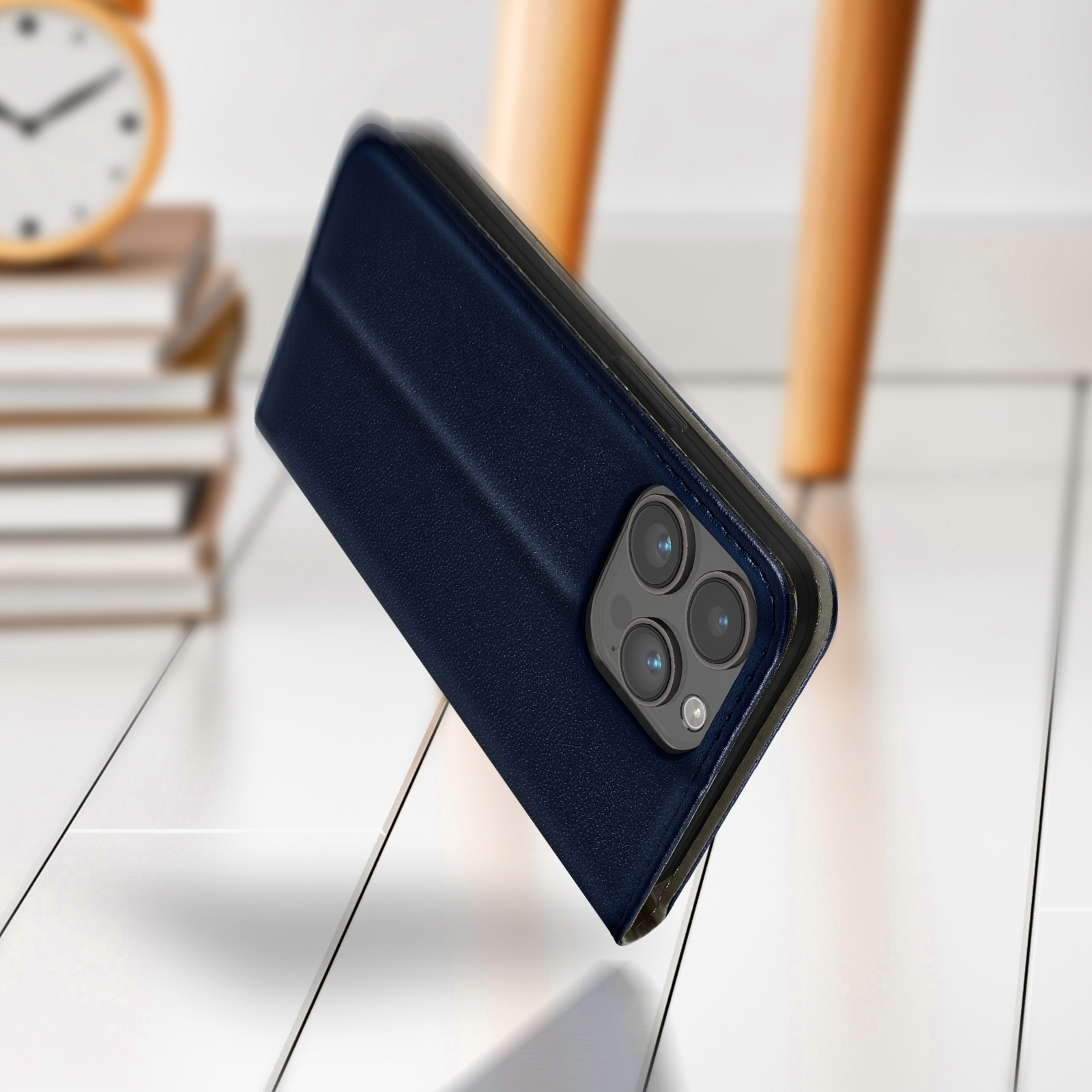 Custodia blu scuro per telefono con tre fotocamere, su pavimento in legno bianco.