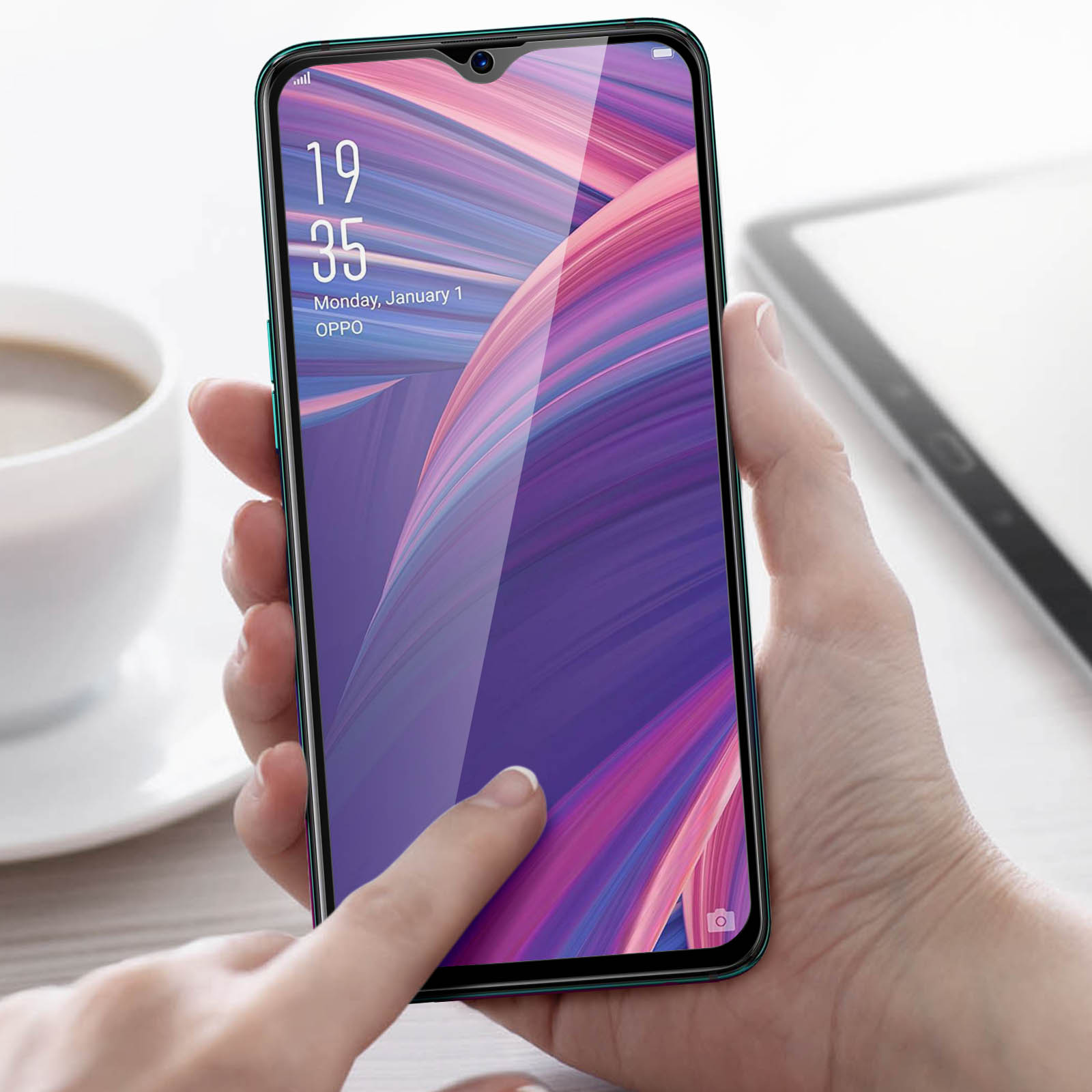 Una mano tiene uno smartphone con sfondo colorato. Una tazza di caffè è a sinistra.