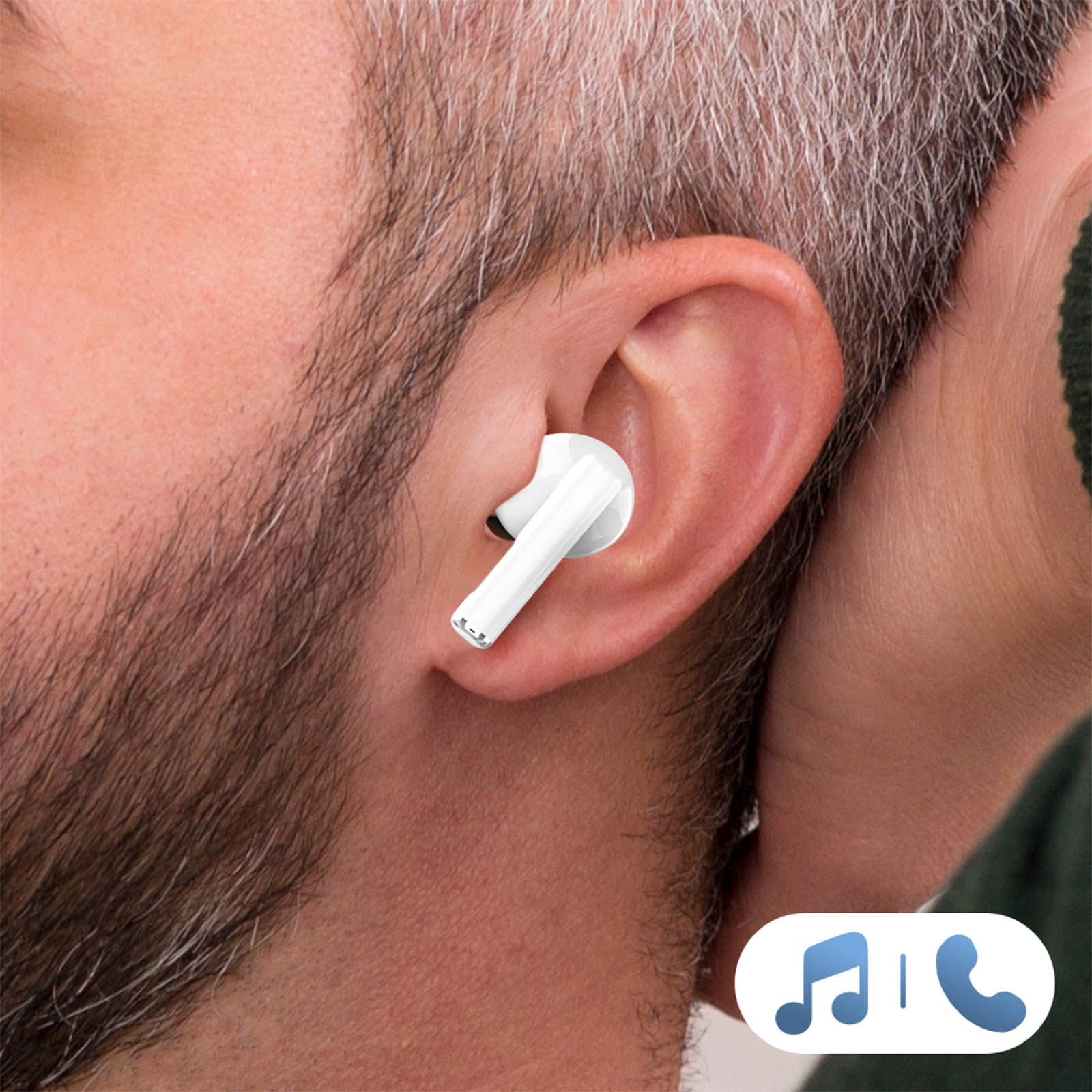 Un uomo indossa un auricolare bianco, mostrando barba e capelli ingrigenti.