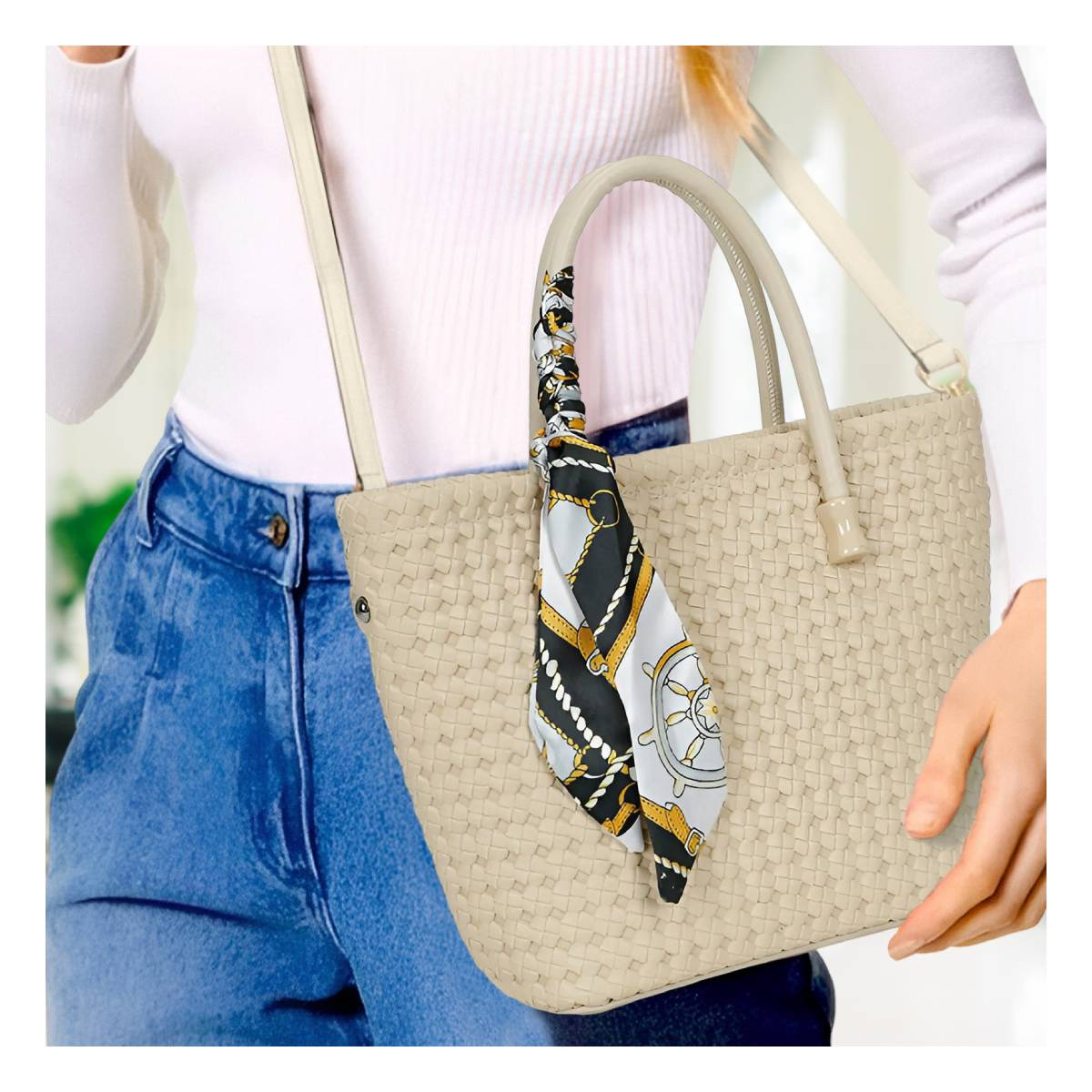 Una persona lleva un bolso tejido beige con un pañuelo estampado en el asa.