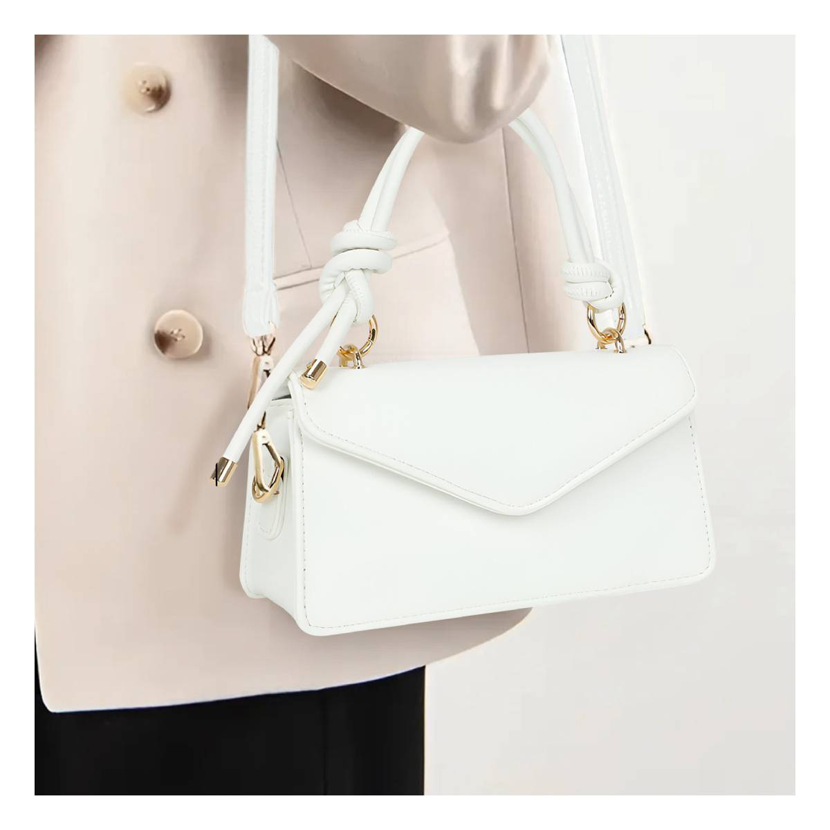 Eine weiße Handtasche mit goldenen Details, gehalten von einer Person in einer cremefarbenen Jacke.