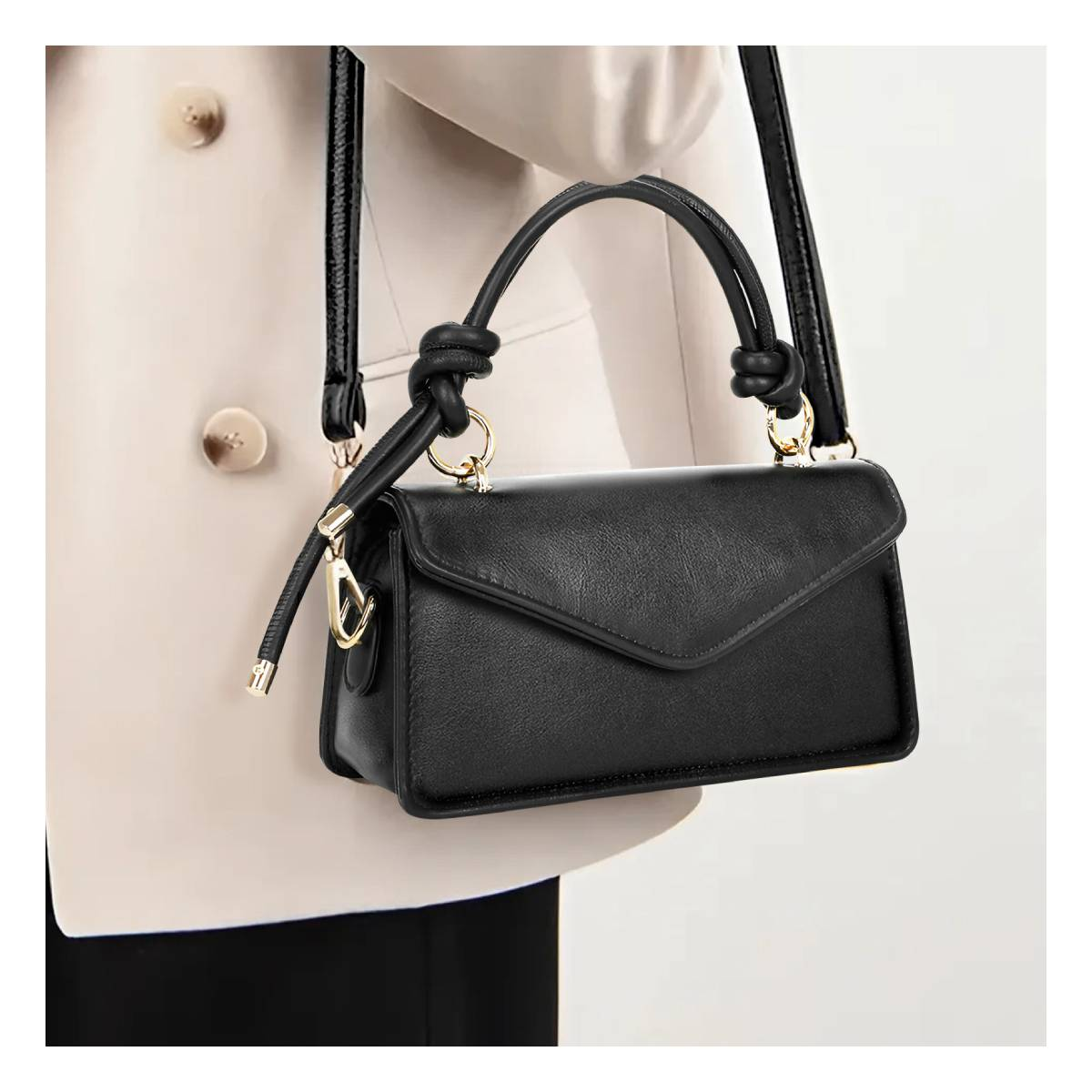 Eine schwarze Lederhandtasche mit goldenen Beschlägen und verdrehten Henkeln wird getragen.