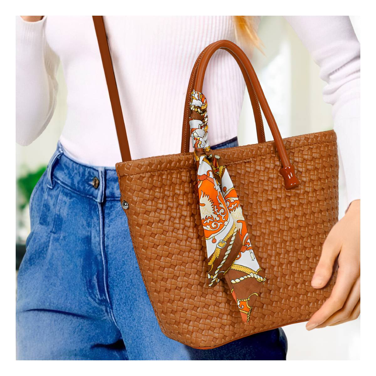 Una mujer lleva un bolso de mimbre con un pañuelo estampado. Vaqueros azules.