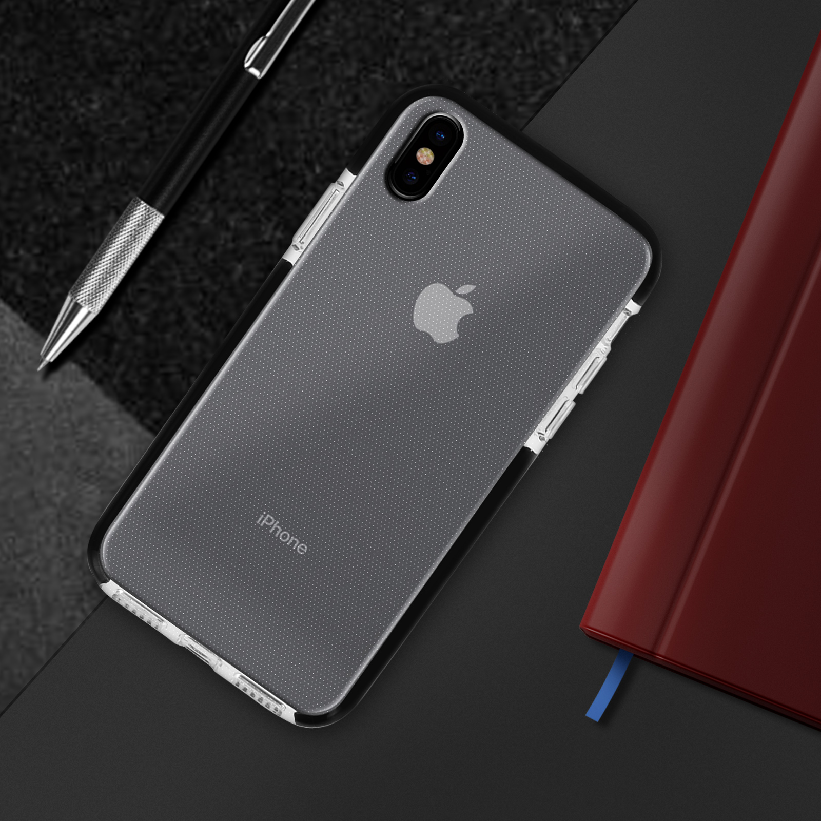 Un iPhone in custodia accanto a una penna e un taccuino rosso.