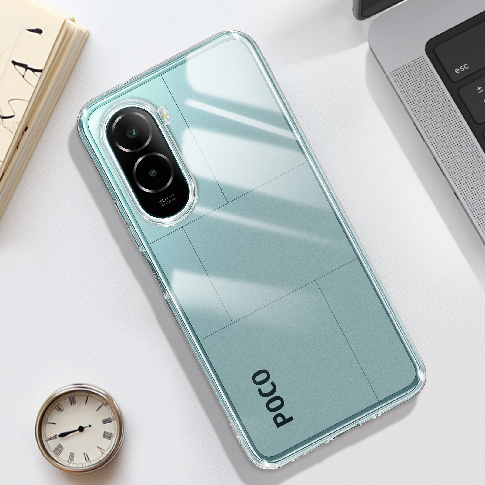 Une coque de téléphone transparente repose sur une table à côté d'un livre et d'une horloge.