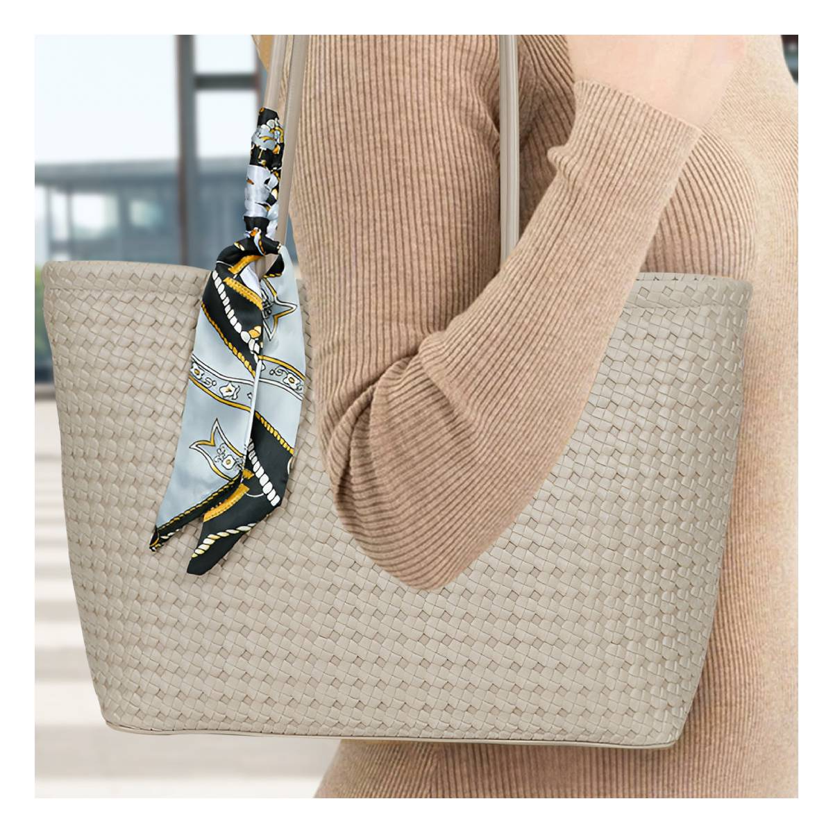 Eine Person trägt eine beige Tasche mit einem gemusterten Schal.