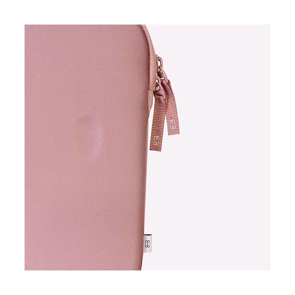 Eine rosa Tasche mit Reißverschluss und zwei kleinen Markenanhängern hängt an der Seite.