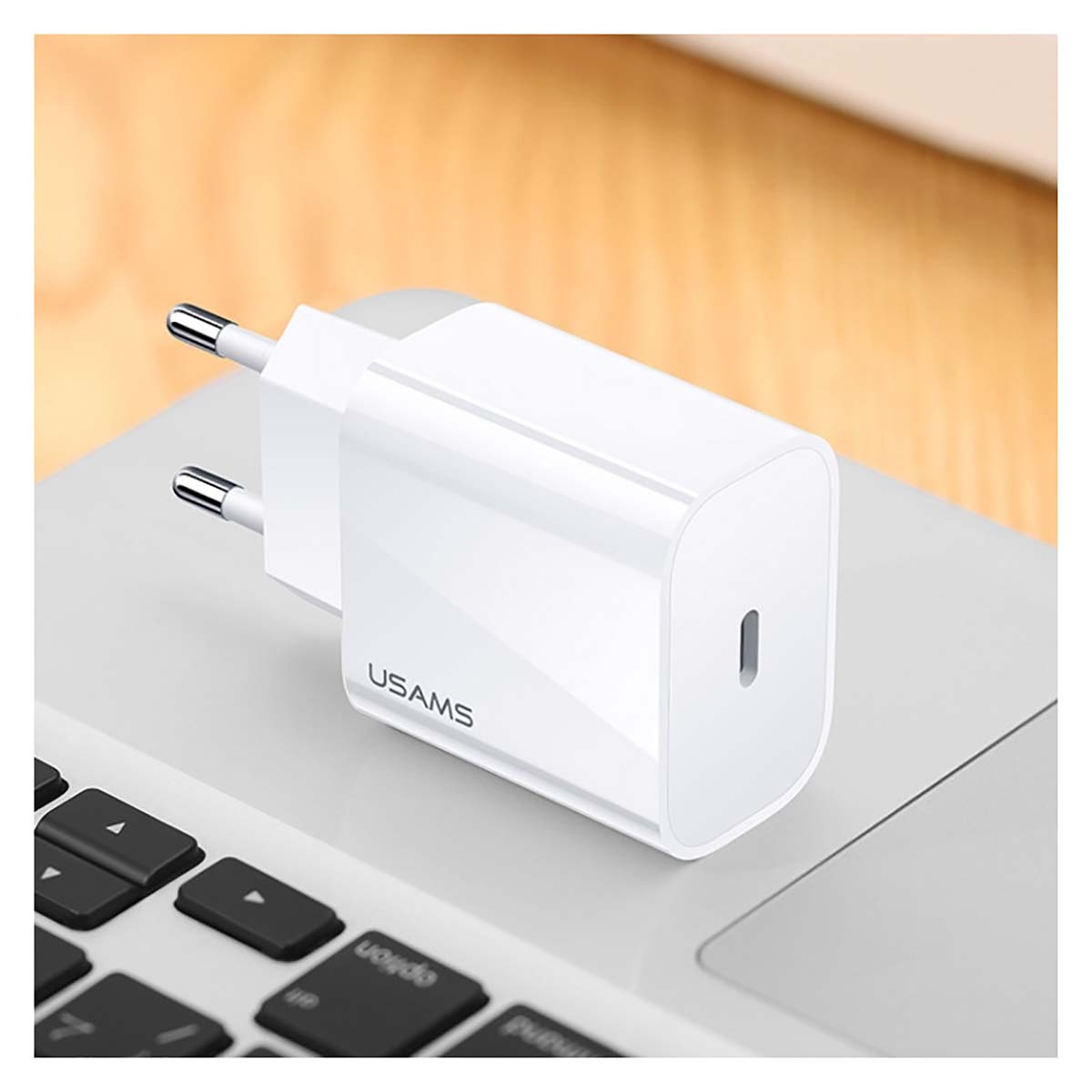 Ein weißer USB-C-Ladestecker mit USAMS-Logo auf einer Laptop-Tastatur.