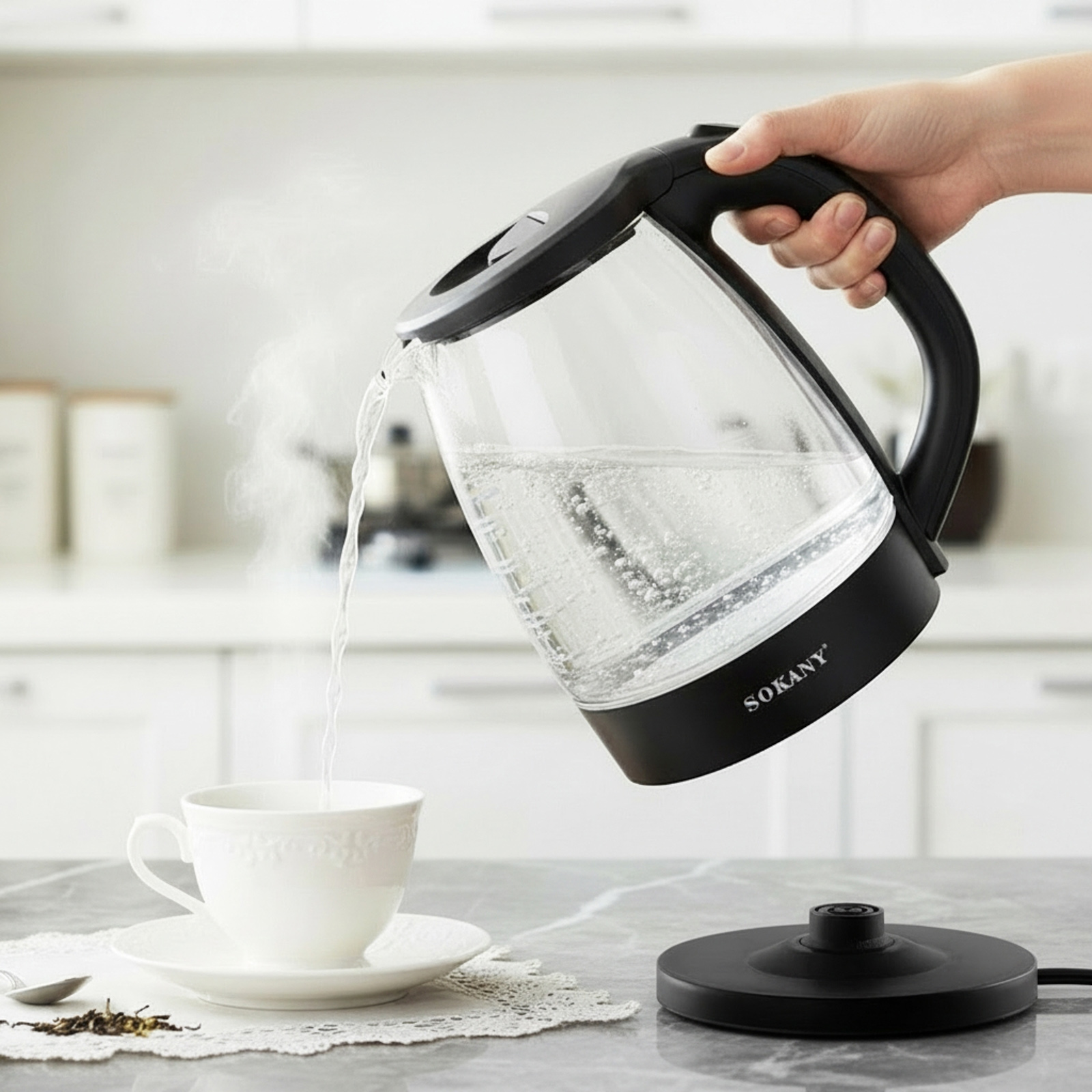 Eine Hand gießt heißes Wasser aus einem Wasserkocher in eine Tasse.
