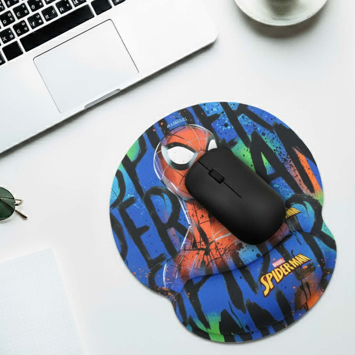 Mousepad Spiderman con mouse nero sopra. Laptop vicino.