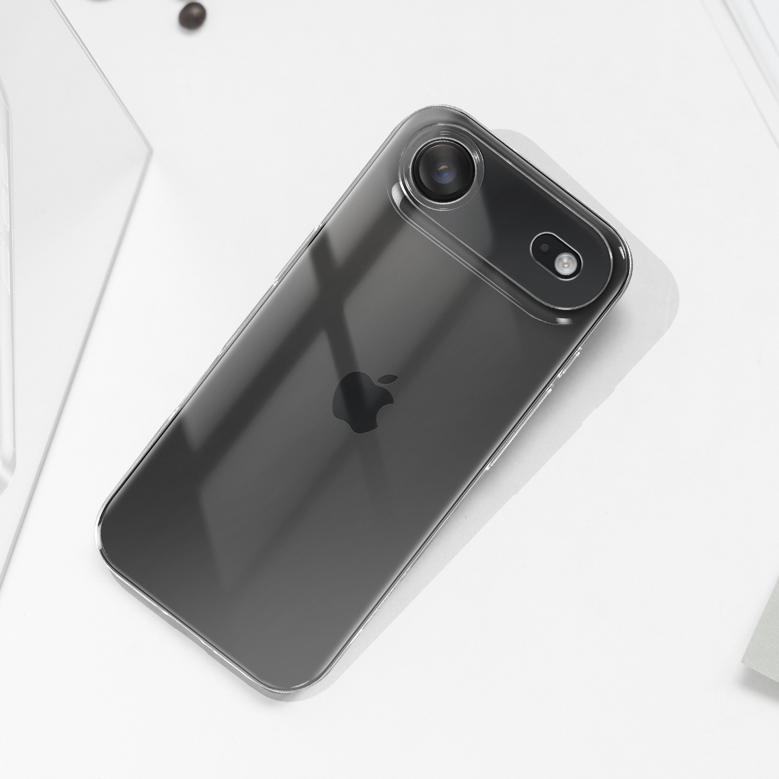 Un iPhone scuro con custodia trasparente e due fotocamere giace su una superficie bianca.
