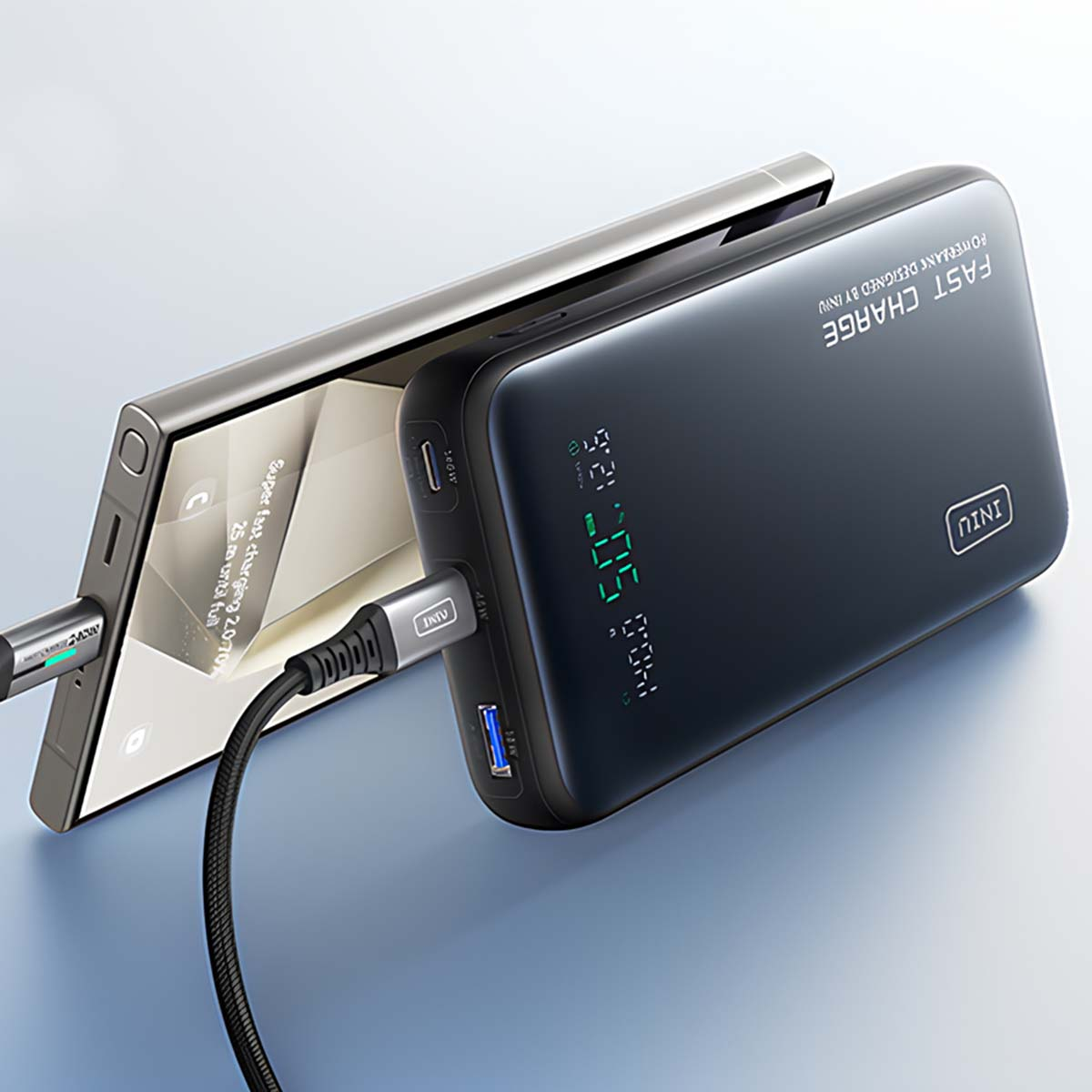 Un smartphone noir est chargé par une power bank avec un port USB bleu.