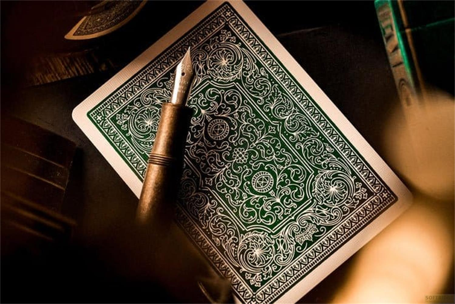 Carte à jouer verte avec motif argenté et un stylo.