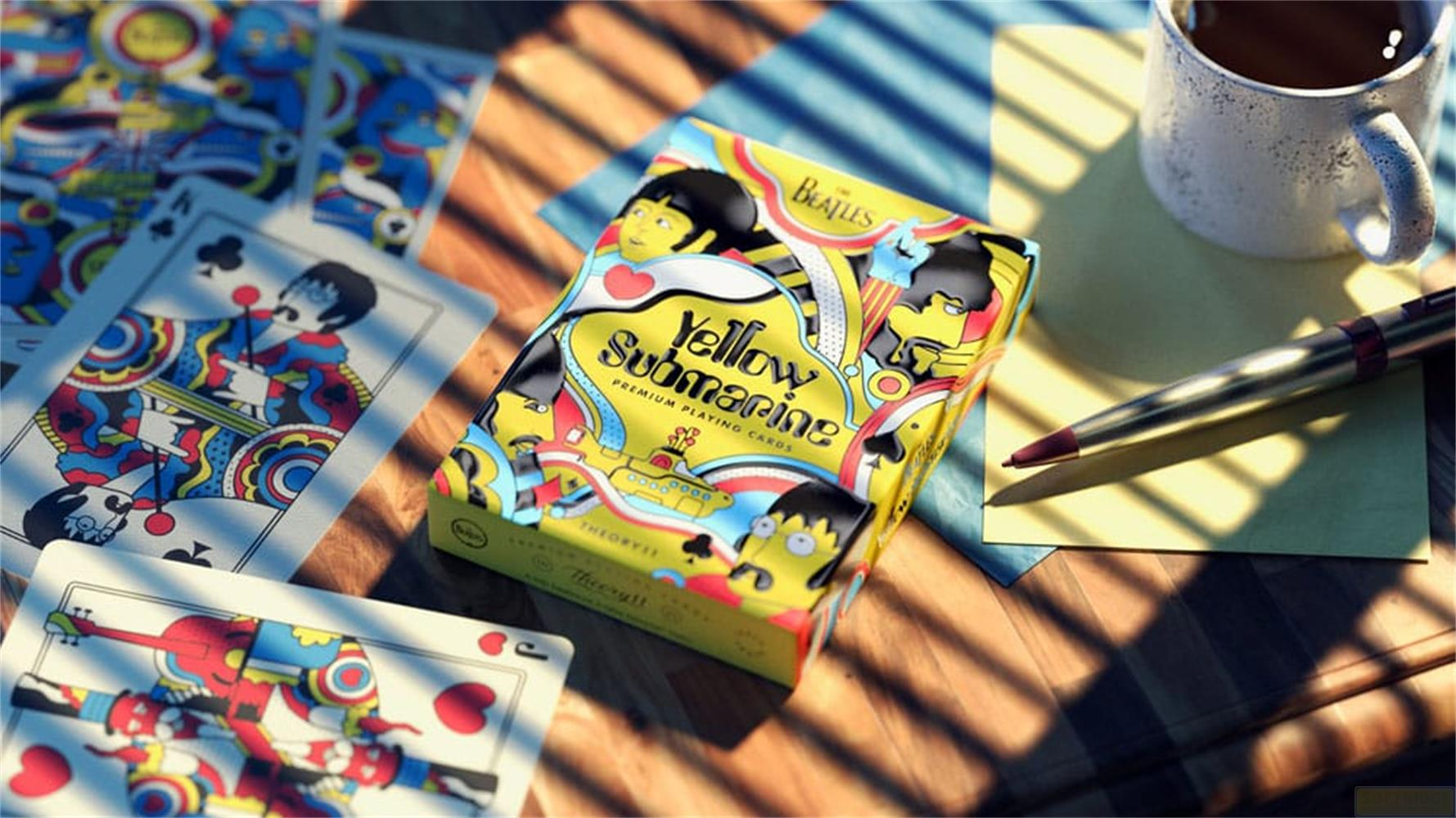 Beatles Yellow Submarine Spielkarten, Tasse Kaffee, Stift und Papier auf Holztisch.