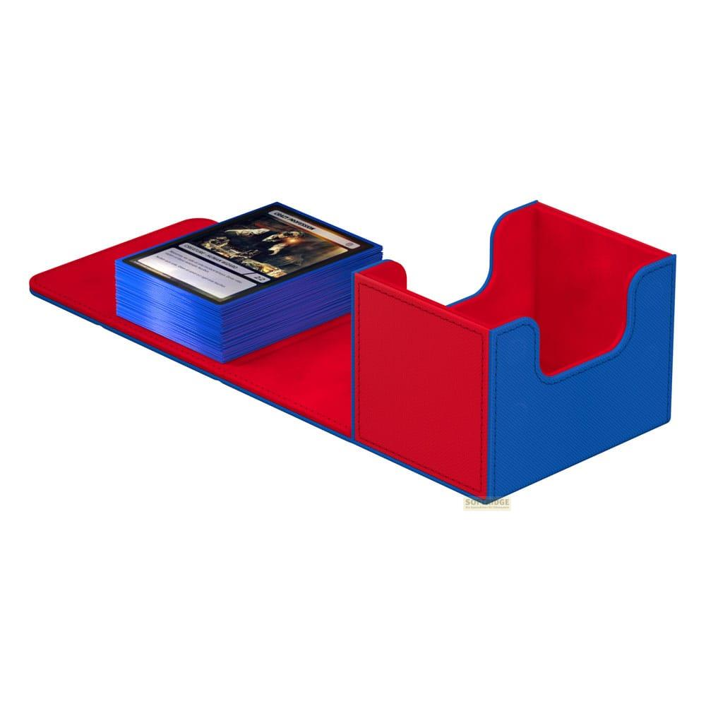 Un mazzo di carte blu poggia su un tappetino rosso accanto a un porta carte rosso e blu.