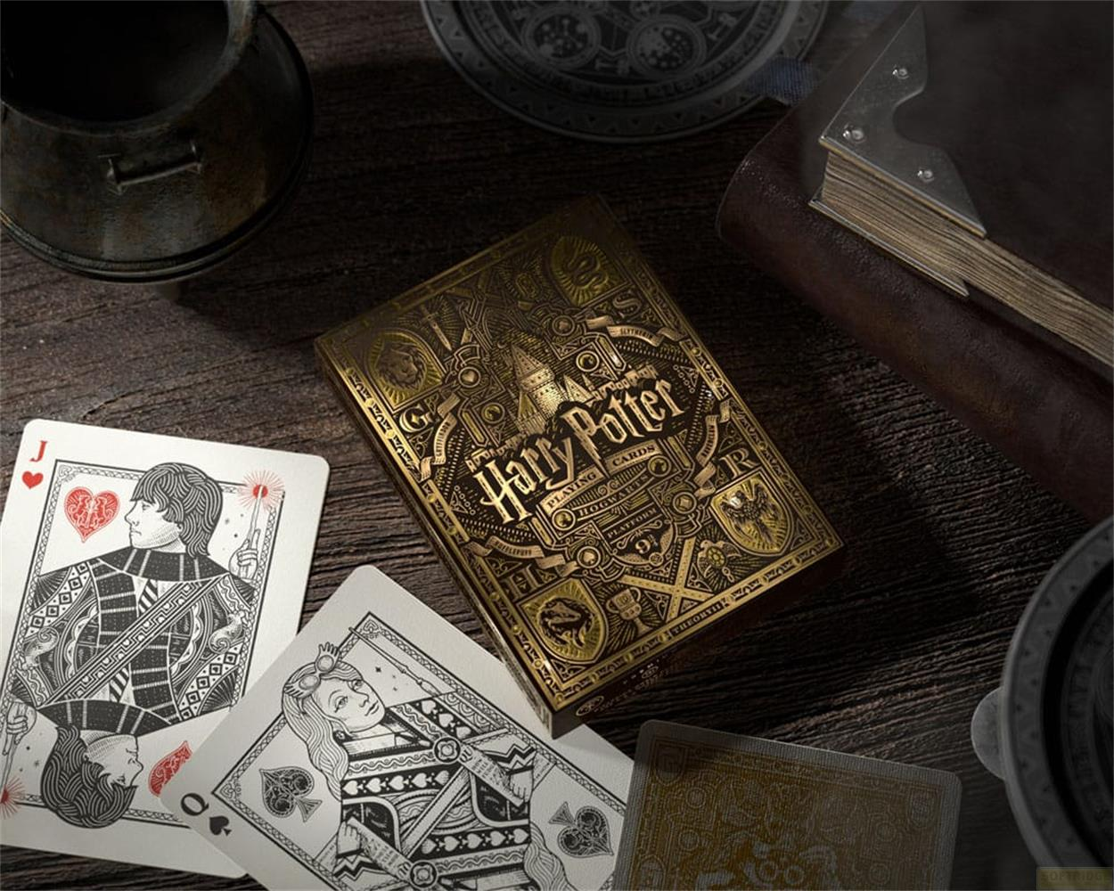 Scatola dorata di carte da gioco Harry Potter con carte aperte su un tavolo di legno.