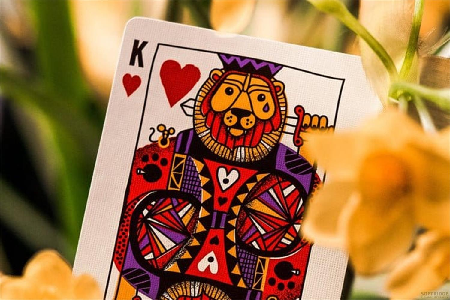 Carta da gioco Re di cuori con design a testa di leone, circondata da fiori gialli.
