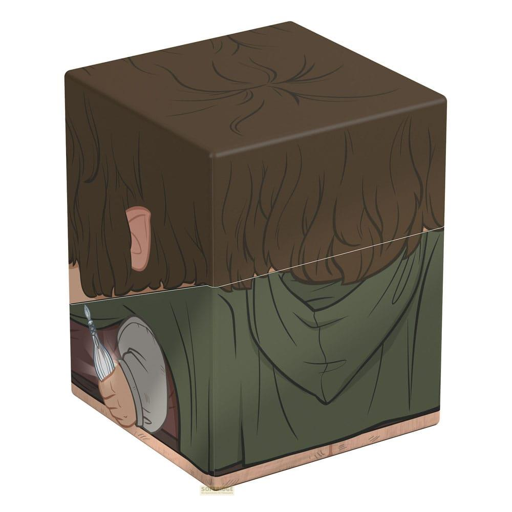 Cheveux bruns et capuche verte sur un cube. Une main tient un objet.