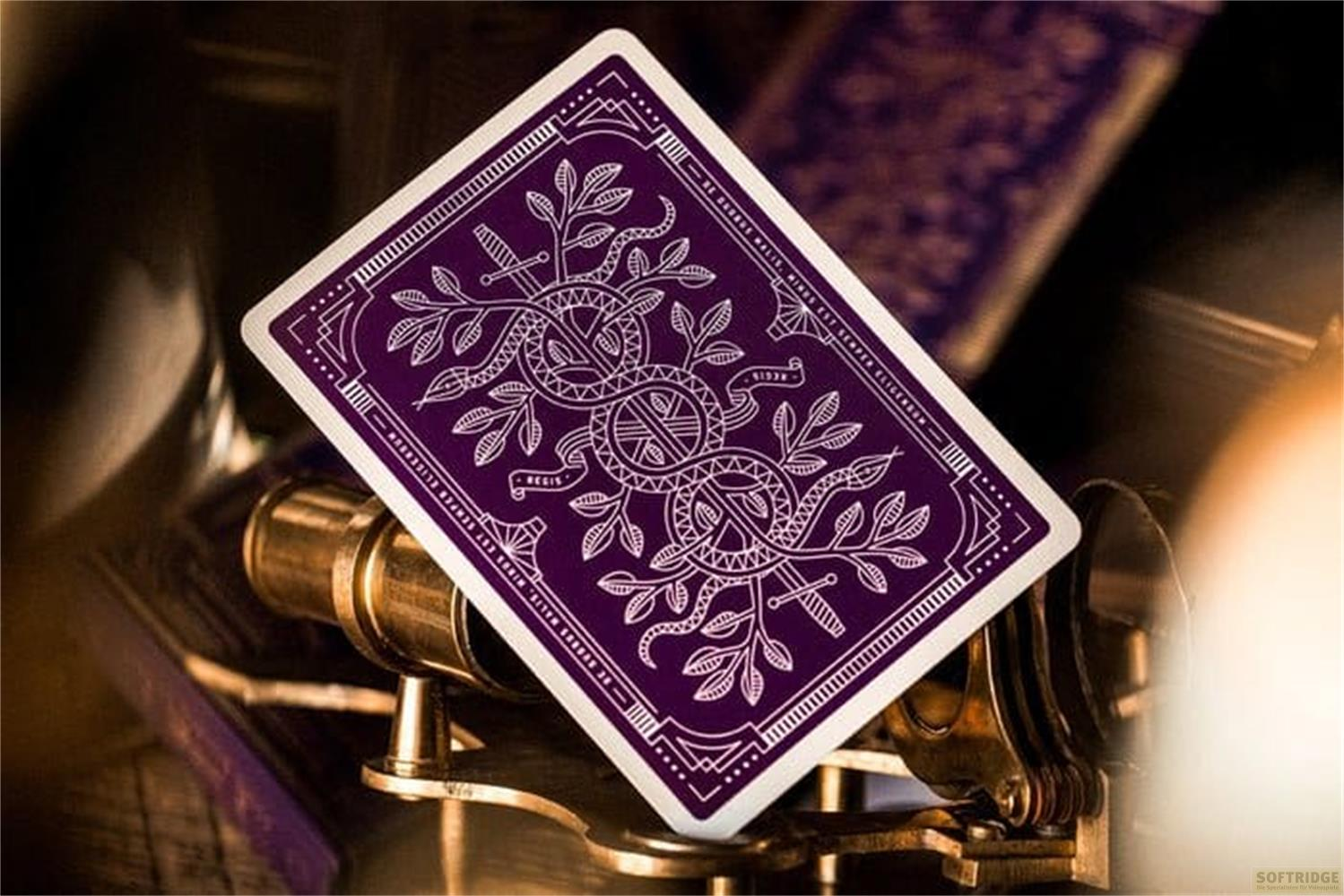 Carta da gioco viola con motivo bianco su supporto in ottone.