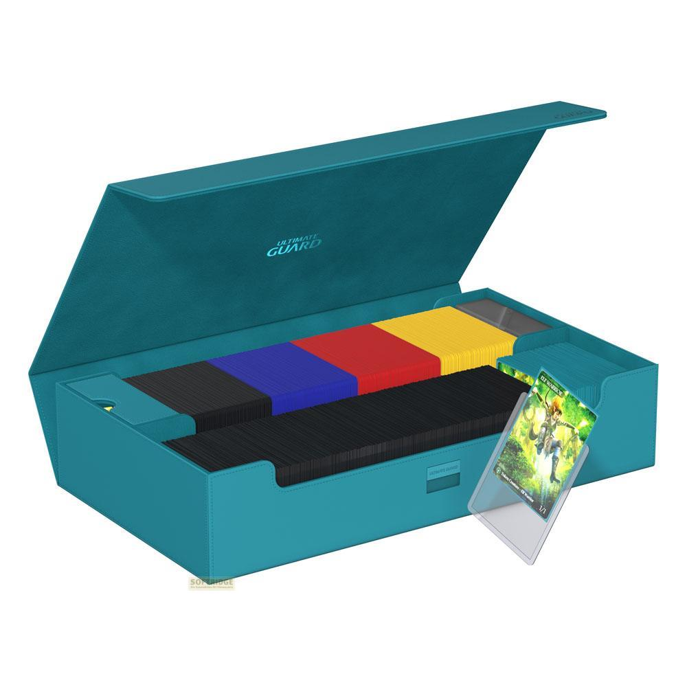 Una scatola porta carte turchese con coperchio aperto, piena di mazzi e una carta da gioco.