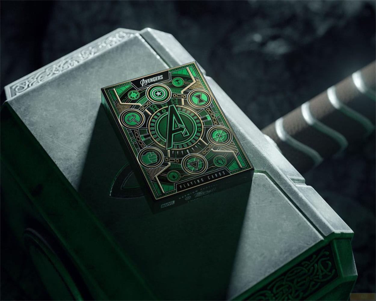 Una carta da gioco verde degli Avengers poggia su Mjolnir, il martello di Thor.