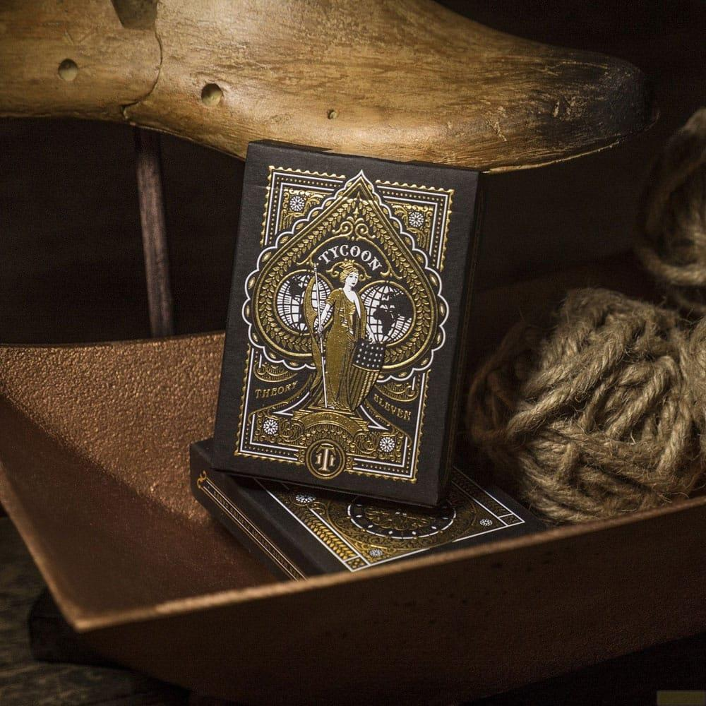 Scatola di carte da gioco nera con decoro dorato, su un piatto di rame.