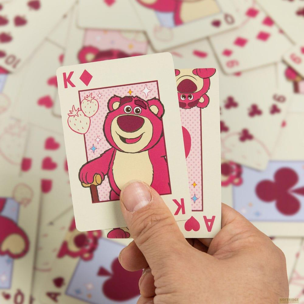 Une main tient des cartes à jouer à l'effigie de Lotso de Toy Story. Un jeu de cartes est en arrière-plan.