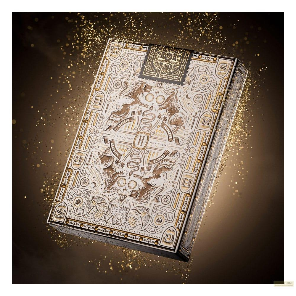 Une boîte de jeu de cartes dorée et blanche aux motifs complexes, entourée de paillettes.