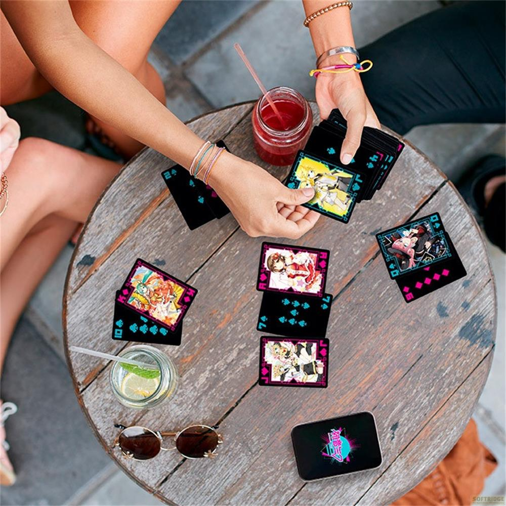 Des gens jouent aux cartes sur une table en bois avec des boissons et des lunettes de soleil.