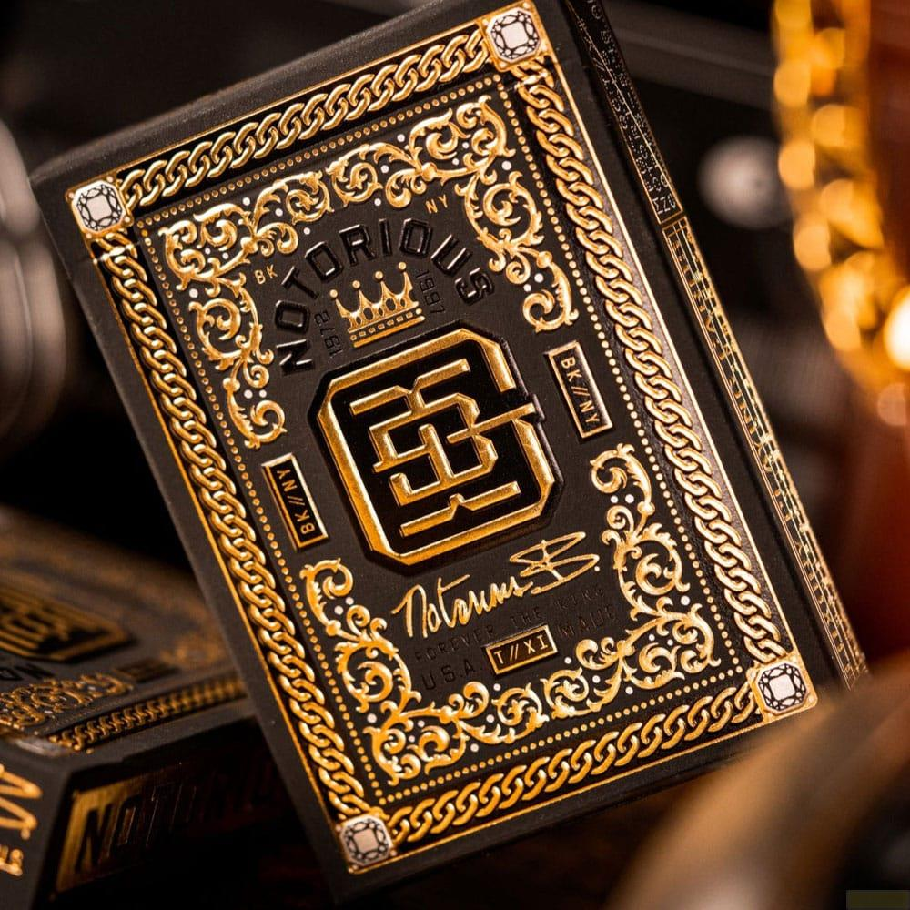 Scatola nera con design dorato ornato, catena e monogramma.