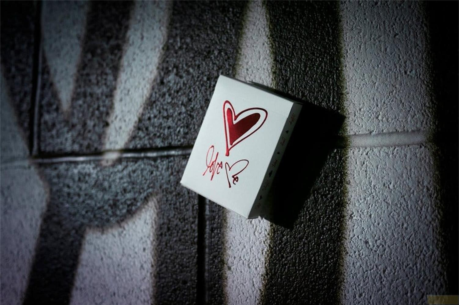 Una scatola bianca con un cuore rosso e testo 'love' su un muro con graffiti.