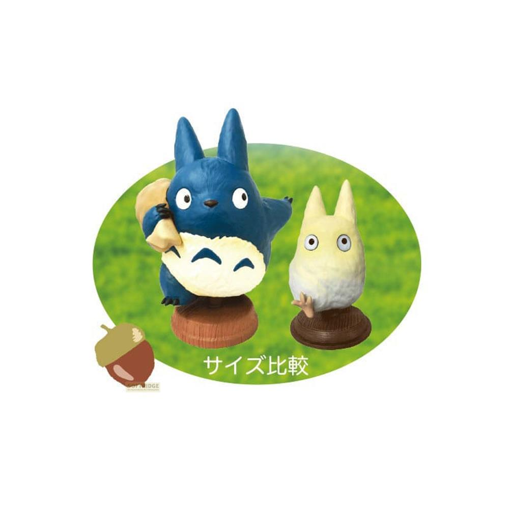 Grande Totoro blu con sacco, piccolo Totoro bianco su sfondo ovale.
