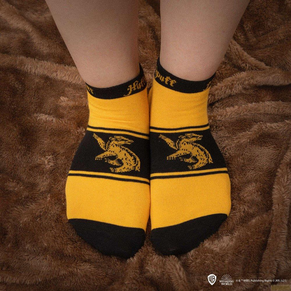 Gelbe Socken mit schwarzem Muster und "Hufflepuff"-Schriftzug auf braunem Untergrund.
