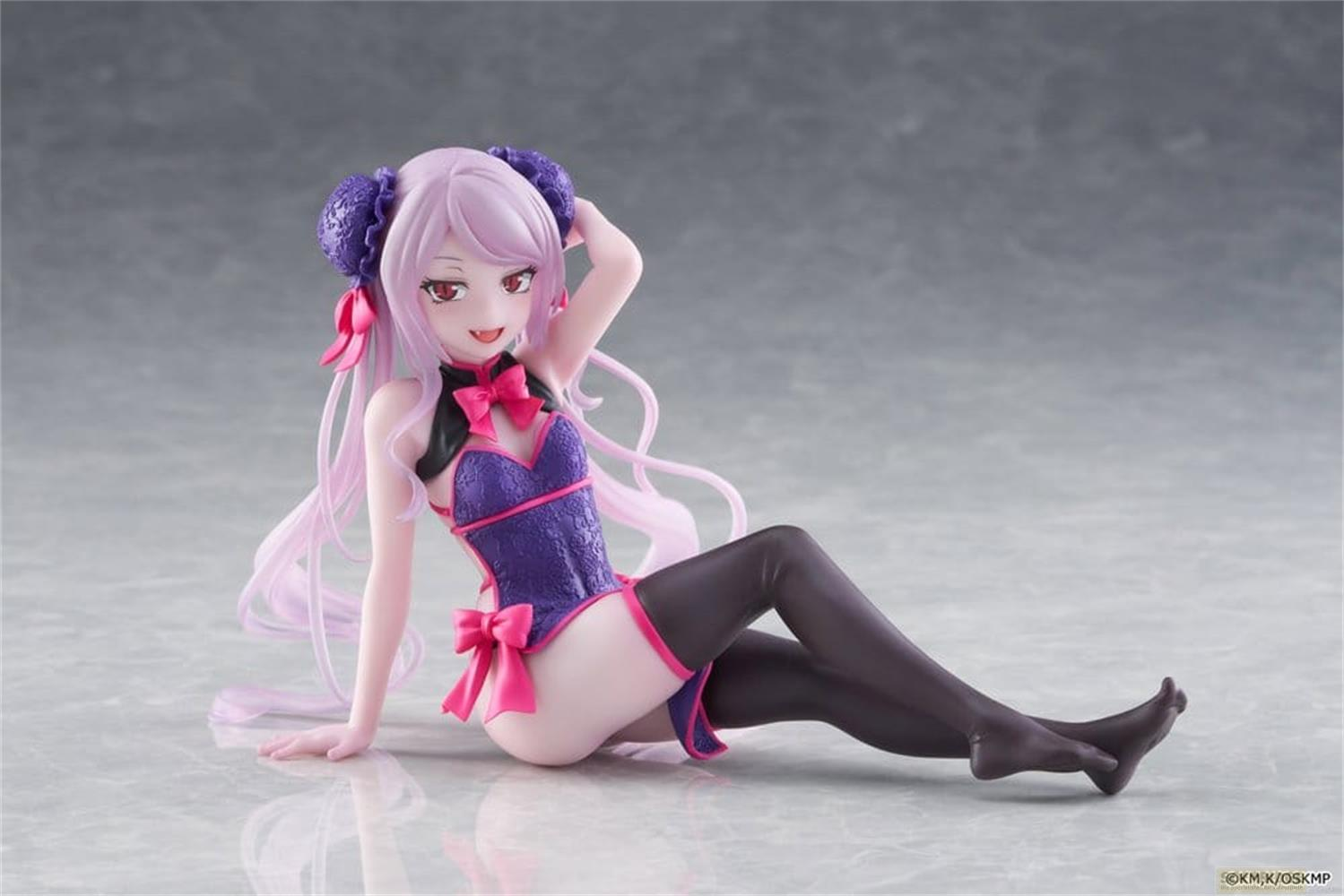 Anime-Figur mit lila Haaren, blau-pinkem Outfit, sitzt auf glänzender Oberfläche.