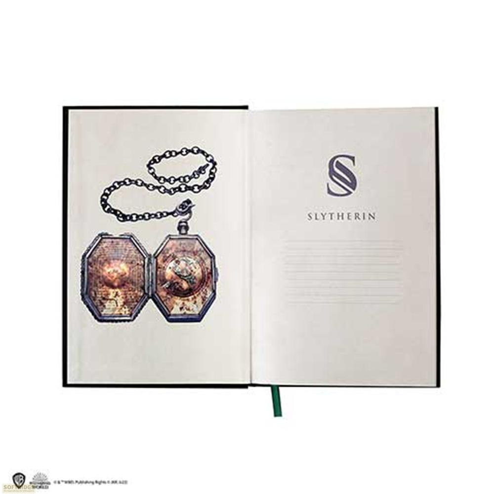 Offenes Notizbuch mit Slytherin-Logo und einer Kette mit einem Medaillon.