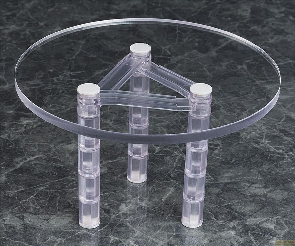 Ein runder, transparenter Acryltisch mit drei Säulenständern auf dunklem Marmorboden.