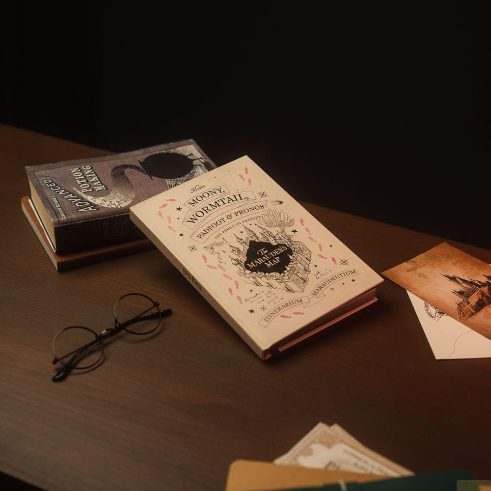Un libro de pociones, el Mapa del Merodeador y gafas sobre una mesa de madera.