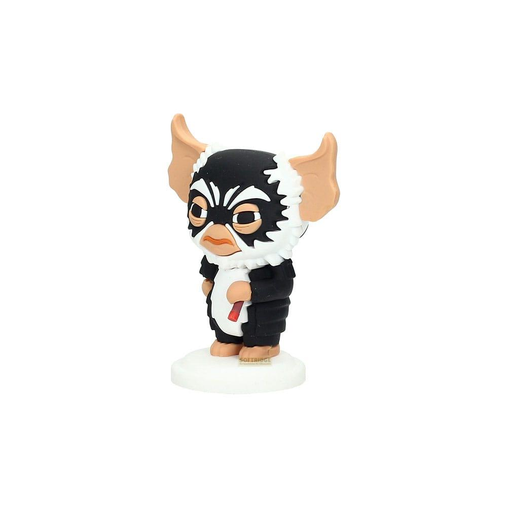 Una pequeña figura de un Gremlin con traje negro está sobre una base blanca.