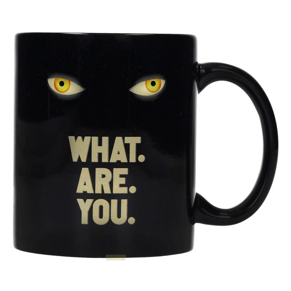 Taza negra con ojos de gato amarillos y texto "WHAT. ARE. YOU."