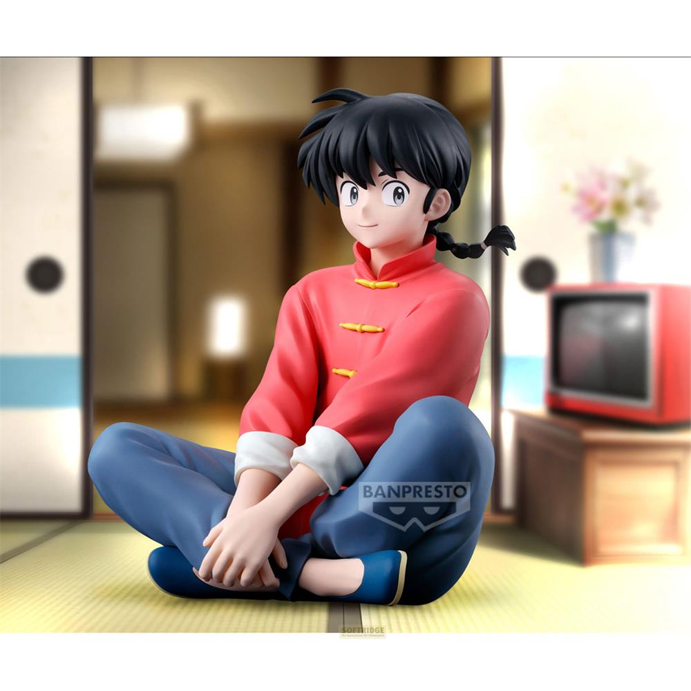 Una figura de anime con traje rojo y pantalones azules se sienta con las piernas cruzadas.