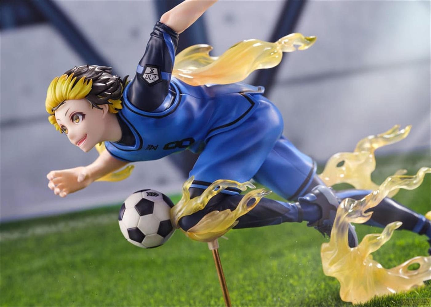 Figura de anime de un futbolista con uniforme azul pateando un balón, con llamas amarillas.