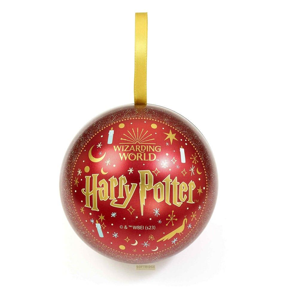 Un adorno rojo y brillante de Harry Potter con texto y símbolos dorados cuelga de una cinta dorada.
