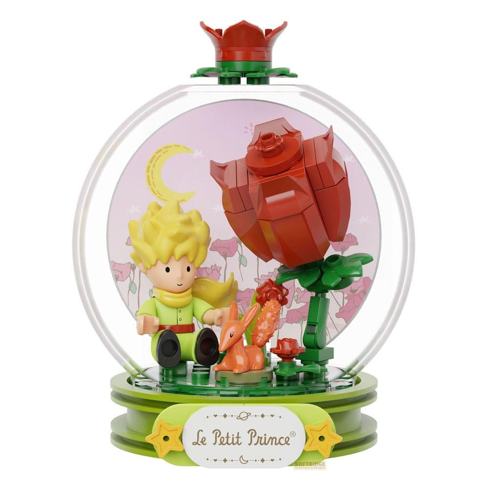 Der kleine Prinz sitzt neben einem Hasen und einer Rose in einer Glaskuppel.