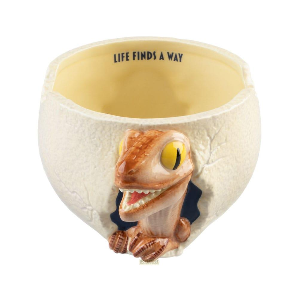 Una taza con forma de huevo de dinosaurio. Un bebé dinosaurio asoma.