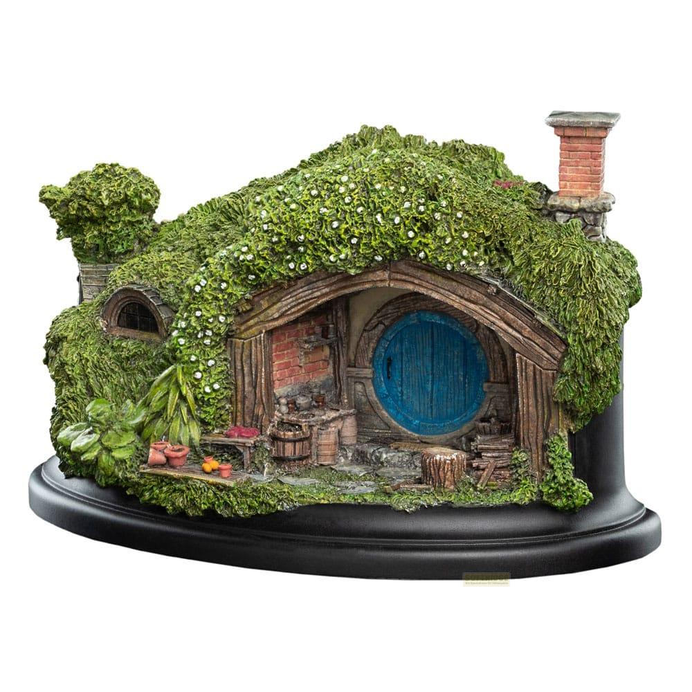 Ein winziges Hobbit-Haus mit runder blauer Tür, bedeckt mit Grün und Blumen.