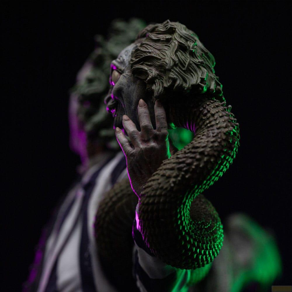 Una mano tocca il volto di un serpente, illuminato da luci verdi e viola.