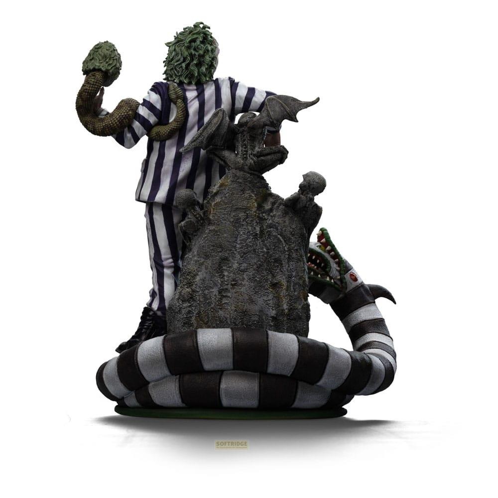 Figura di Beetlejuice in abito a righe tiene un serpente, davanti a una roccia con drago.