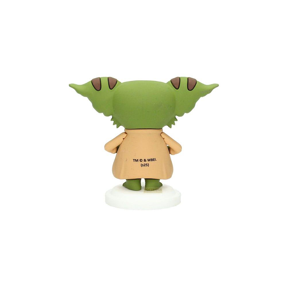 Personaje verde con orejas grandes, viste túnica beige, sobre base blanca.